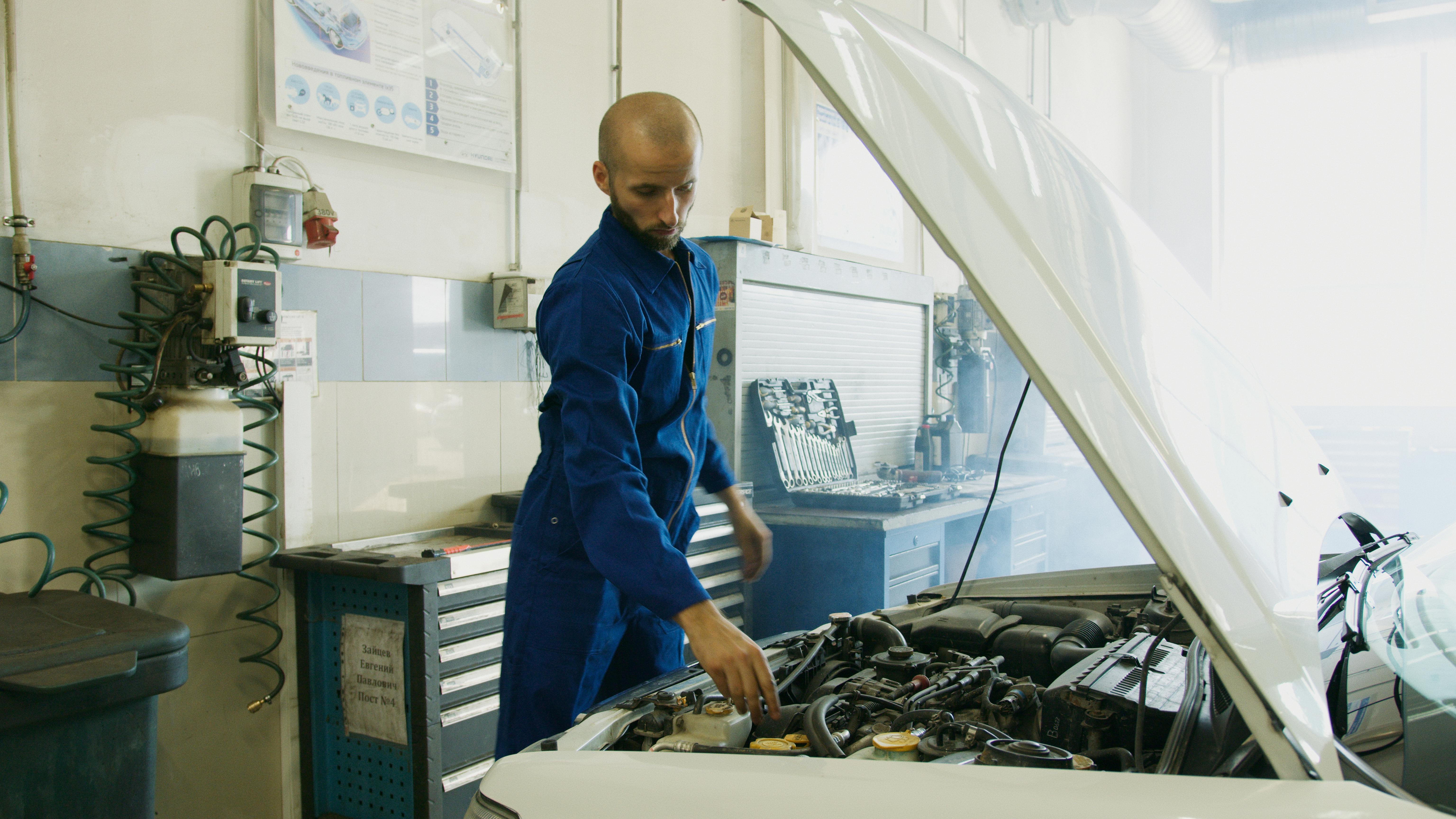DVLA MOT checker — mechanic inspecting car engine bay at UK garage