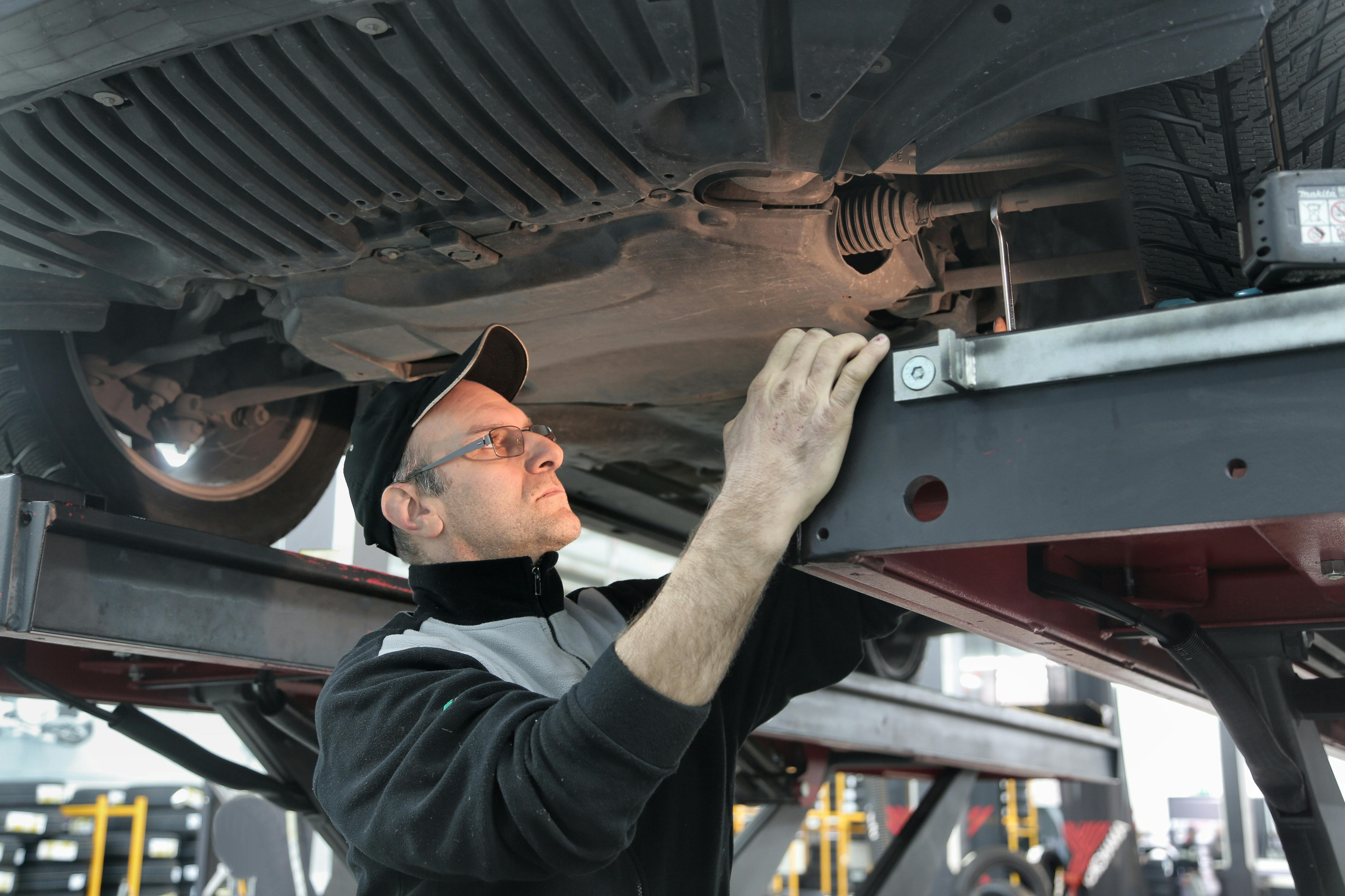 MOT checker Northern Ireland — mechanic inspecting car underside at NI test centre